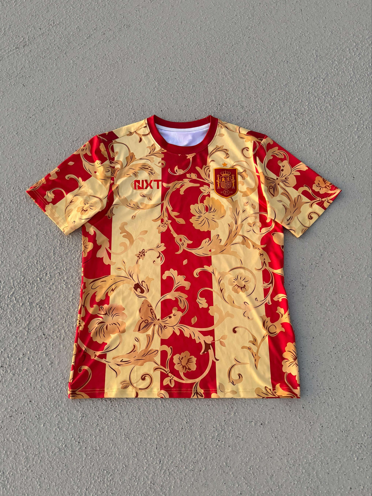 NXT ESPAÑA Red & Gold Floral Concept Jersey showcasing Spanish style and heritage.