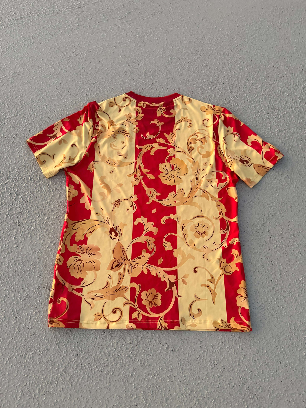 NXT ESPAÑA exclusive Red & Gold Floral Concept Jersey featuring bold red and soft gold vertical stripes.